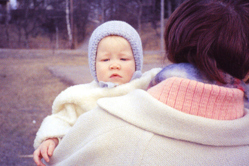 baby in winter hat being carried by adult